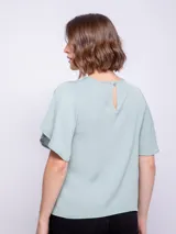 Top rosado de mangas cortas con volados, cuello redondo y detalle diagonal en el frente.