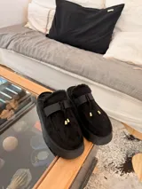 Suecos de símil gamuza color beige, con interior forrado en corderito sintético, plataforma y detalle de tira frontal con cordones y punteras metálicas.