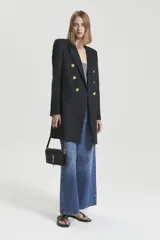 Saco largo negro de lino con acceso cruzado, silueta recta y hombreras altas. Tiene botones dorados.