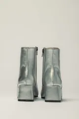 Botas cortas plateadas de cuero con puntera negra, taco cuadrado y cierre lateral.