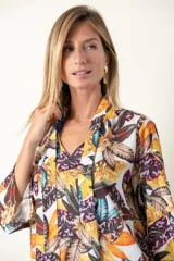 Blusa estampada con hojas en tonos mostaza, verde y blanco. Tiene cuello con lazo, manga tres cuartos y cintura fruncida.
