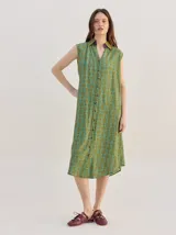 Vestido midi camisero sin mangas, de corte recto y holgado. Cuenta con cuello camisero liso en color naranja y cierre frontal parcial con botones. Presenta un estampado geométrico psicodélico en tonos naranja y beige.