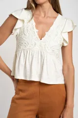 Remera color crudo de algodón con calados, corte al cuerpo y mangas cortas con volados.