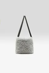 Cartera de hombro gris con textura peluda y correa larga ajustable.