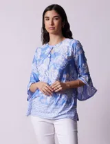 Blusa azul con estampado floral blanco, de seda fría, con cuello redondo con abertura y mangas 3/4 amplias con volados. Marca Ruby Rd.