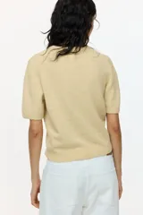 Remera corta de punto suave color amarillo, de manga corta, con cuello redondo y terminaciones acanaladas.