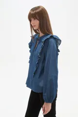 Blusa de jean con volados frontales, cuello redondo con abertura en V y lazo para anudar, y mangas largas con puños elásticos.
