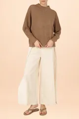 Suéter de punto con acabado metalizado en color dorado, de silueta holgada, cuello alto y mangas largas con puños ajustados.