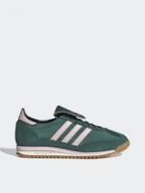 Zapatillas Adidas modelo SL 72 OG LT, de diseño retro inspirado en el running y el fútbol. Presentan un cuerpo de gamuza en color verde oscuro con las icónicas tres tiras laterales en tono rosado claro. Incluyen una lengüeta larga distintiva, entresuela blanca con detalles en rosa y suela de goma dentada color caramelo.