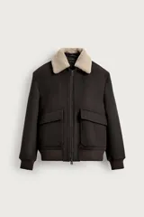 Cazadora relaxed fit color marrón oscuro de tejido con lana y cashmere, con cuello solapa desmontable de borreguillo en tono tostado. Cuenta con mangas largas con puños de rib, bolsillos de plastrón con solapa en la cadera, cierre frontal de cremallera y acabado elástico en el bajo.