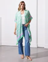 Kimono tejido con estampado abstracto en tonos azules, blancos y violetas. Tiene terminación de ruedo con borlas.