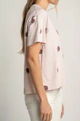 Remera rosa de algodón con estampado de lunares marrones.