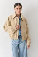 Campera bomber de paño color beige, con cierre frontal, cuello alto y puños elásticos.