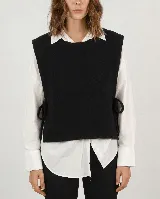 Chaleco de punto negro con diseño abierto en los laterales, ajustado mediante lazos laterales. Presenta un corte recto y cuello redondo.