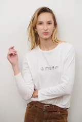 Remera de manga larga color blanco, con cuello redondo y diseño de bordado lineal en el centro del pecho que representa elementos de desayuno.