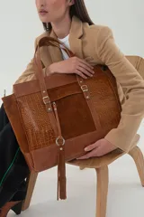 Bolso tote de cuero vacuno color marrón, con paneles de cuero graneado, gamuza y textura croco. Tiene doble asa fija, correa larga regulable y desmontable, bolsillo frontal con cierre invisible, borla de cuero con aro metálico, forro textil con bolsillo interno con cierre y divisor porta objetos.