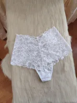 Bombacha tipo hipster confeccionada íntegramente en encaje floral blanco, con diseño de tiro alto y cobertura trasera moderada.
