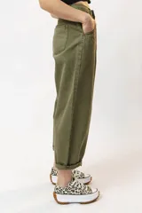 Pantalón de jean color verde oliva, de corte holgado y tiro alto, con pinzas en la cintura y bolsillos laterales.