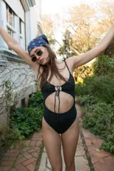 Traje de baño entero negro con breteles finos y escote con abertura ajustable en el centro.