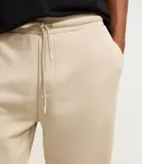 Pantalón tipo jogger de corte holgado, color verde oliva, con cintura elástica ajustable mediante cordón, bolsillos laterales y puños elásticos en los tobillos.