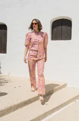 Camisa de lino con estampado floral en tonos rosados y naranjas, de corte recto, cuello mao y cierre frontal con botones. Presenta mangas al codo con frunces en los hombros.