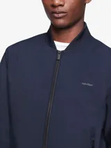 Campera bomber azul marino de poliéster y algodón, con cuello redondo, cierre frontal completo, bolsillos laterales con cierre, logo de Calvin Klein en el pecho y ribete de punto acanalado.