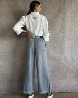 Pantalón de jean gris claro con corte palazzo y cintura alta.