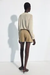 Falda pantalón cruzada de tiro medio en color tostado, con diseño estilo cargo que incluye bolsillos de parche con solapa y detalle de argolla metálica. Cuenta con trabillas y un cinturón integrado con hebilla metálica.