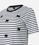 Blusa de media malla a rayas horizontales blancas y negras, con cuello redondo y mangas cortas. Aplicación de moñas negras.