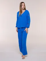 Blusa azul de corte holgado y fluido, con escote en V y mangas largas raglán que presentan detalles de calados con forma de flores y puños elastizados.