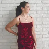 Vestido corto de terciopelo color borgoña, con escote recto, tirantes finos regulables, espalda baja y tiras cruzadas en la espalda. Diseño ajustado con frunces laterales.