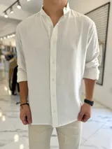Camisa oversize de lino color blanco, con cuello mao, manga larga y cierre frontal de botones.