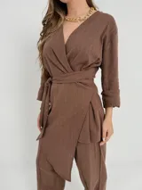 Conjunto de dos piezas confeccionado en lino color beige, compuesto por un pantalón de corte recto y un blazer cruzado con lazo ajustable en la cintura y escote en V.