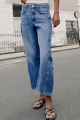 Jeans de tiro medio con cinco bolsillos, pernera holgada y diseño barrel, con costuras decorativas frontales y cierre de cremallera y botón.