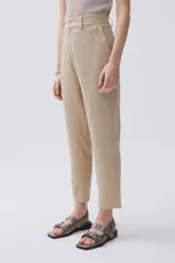 Pantalón chino color beige confeccionado en lino metalizado, de tiro medio-alto y pierna recta. Cuenta con bolsillos laterales y en la espalda.