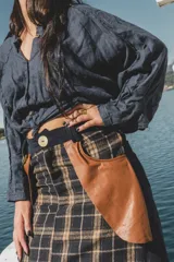 Falda larga de lana con estampado tweed a cuadros en tonos marrón y negro. Presenta detalles de cuero marrón en los bolsillos laterales y botón de guampa en la cintura.