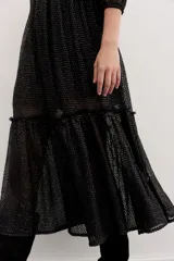 Vestido largo de tul negro con bordados de lentejuelas y canutillos, mangas tres cuartos abullonadas, cintura fruncida y falda con volado en el ruedo.
