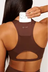 Top deportivo marrón con diseño nadador, entrada para almohadillas removibles, bolsillo trasero y detalle reflectivo.