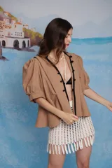 Falda mini tejida en crochet color crudo, con diseño de red y terminación en flecos largos en el ruedo.