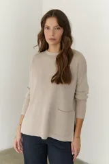 Buzo de tejido de punto acanalado en color beige, con cuello redondo, mangas largas y un bolsillo frontal aplicado en la parte inferior.