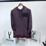 Canguro oversize bordó con efecto lavado, capucha con cordones ajustables y bolsillo tipo canguro. Estampa en la espalda con el logo de la marca Duxon Jeans y el texto "Est. 1982 London".