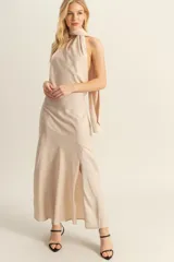 Vestido largo de satén color beige, con escote halter, espalda descubierta y tajo lateral en la falda.