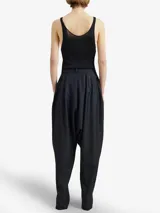 Pantalón negro de lana virgen, inspiración sarouel, con pliegues delanteros estructurados y cierres metálicos frontales de largo completo.