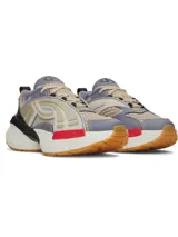Championes Under Armour modelo UA Arc 96, con diseño futurista de inspiración retro. Capellada de malla múltiple en tono beige con superposiciones de cuero y paneles laterales translúcidos. Incorpora detalles en gris, negro y un toque de rojo, con entresuela voluminosa y suela de goma color caramelo.