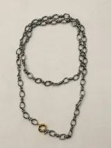 Collar de cadena larga con eslabones ovalados alargados y cierre tipo sailor clasp, con dije colgante en forma de corazón de piedra oscura. Acabado dorado.