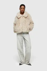 Chaqueta corta de piel sintética peluda, color mostaza/amarillo ocre, con cuello solapa y cierre frontal de cremallera de color amarillo claro.