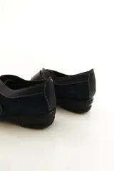 Zapato de cuero negro con cierre de velcro ancho y costuras pespunteadas a contratono.