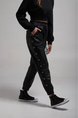 Pantalón negro de cuero sintético con bolsillos laterales y botones metálicos a presión en los laterales.
