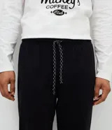 Pijama largo compuesto por una remera de manga larga blanca con cuello redondo en contraste y estampa frontal de Mickey Mouse, y un pantalón largo liso de color negro con cintura elástica.