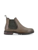 Botin tipo chelsea de cuero graneado color oliva, con paneles laterales de tejido grueso en tono verde oscuro. Presenta suela track dentada y tirador trasero para facilitar el calce.